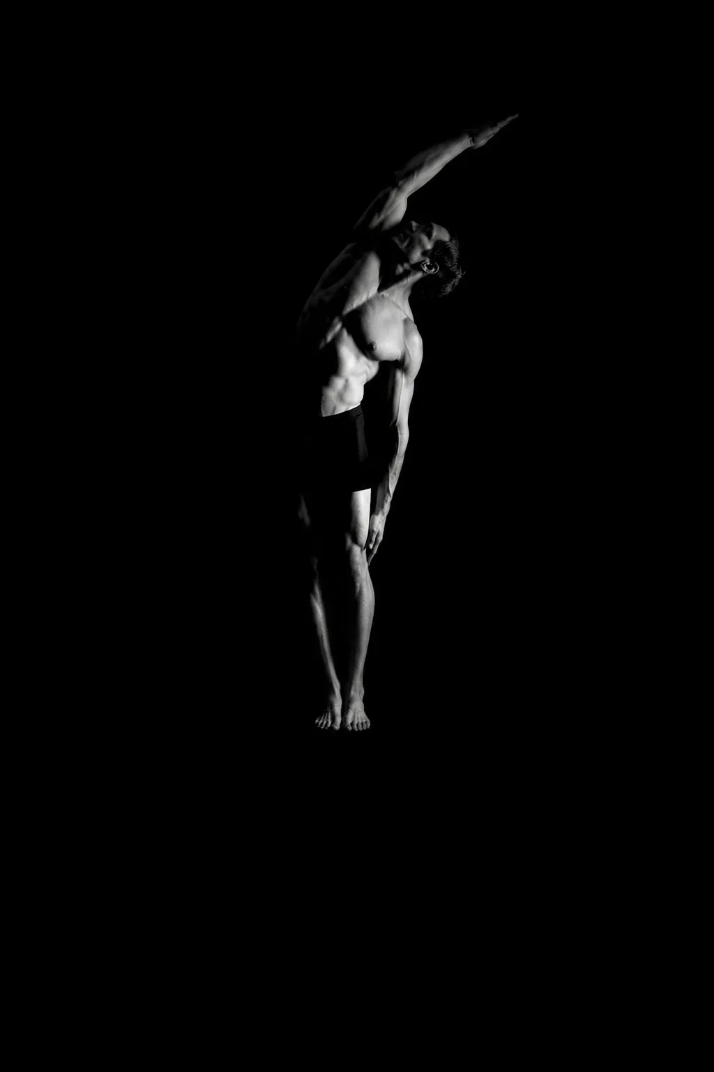 Athlete mid recovery stretch, studio light, grayscale